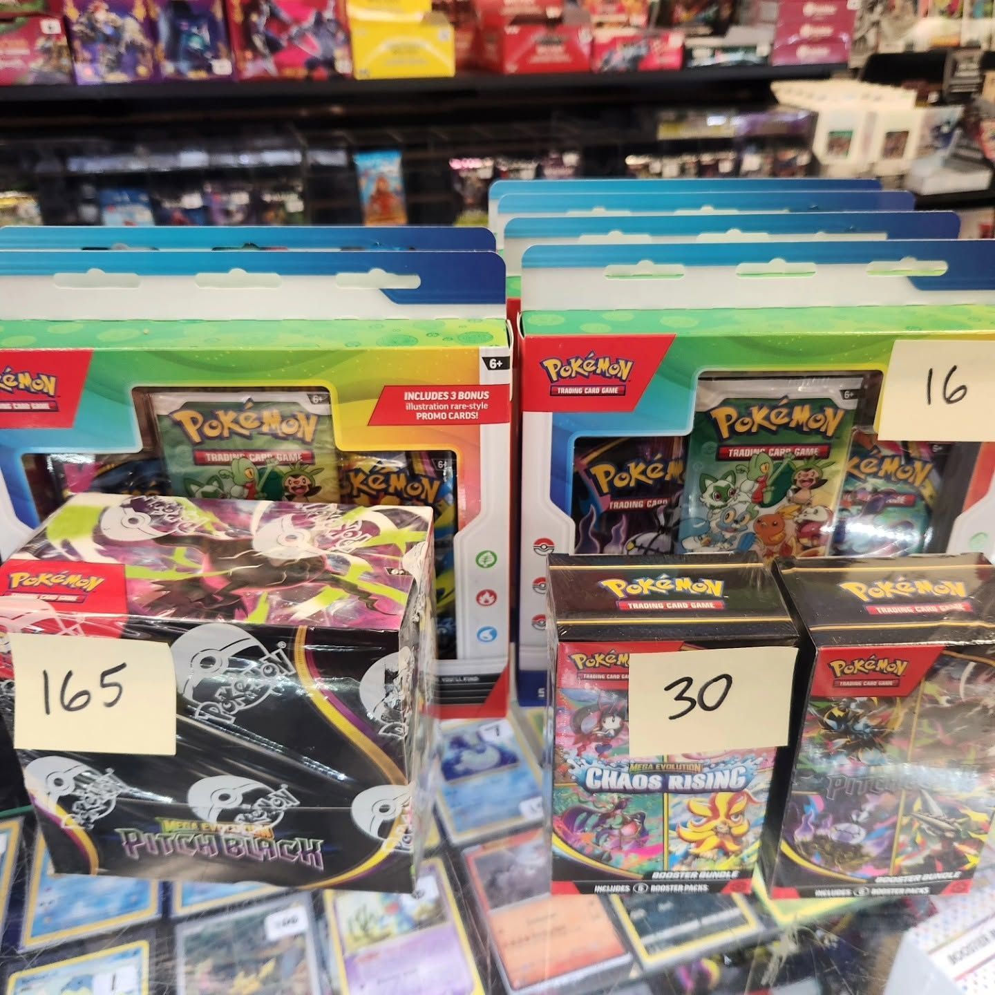 Pokemon trading card boxes on store shelves with price tags, including one marked 165 and another 30