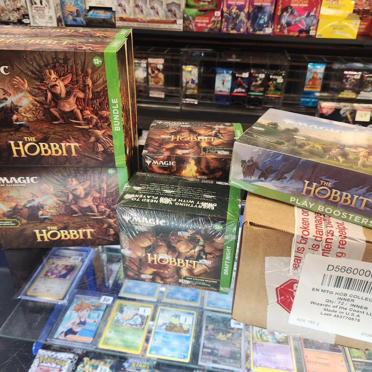 Magic: The Hobbit trading card boxes and cards displayed on a store counter under bright lights