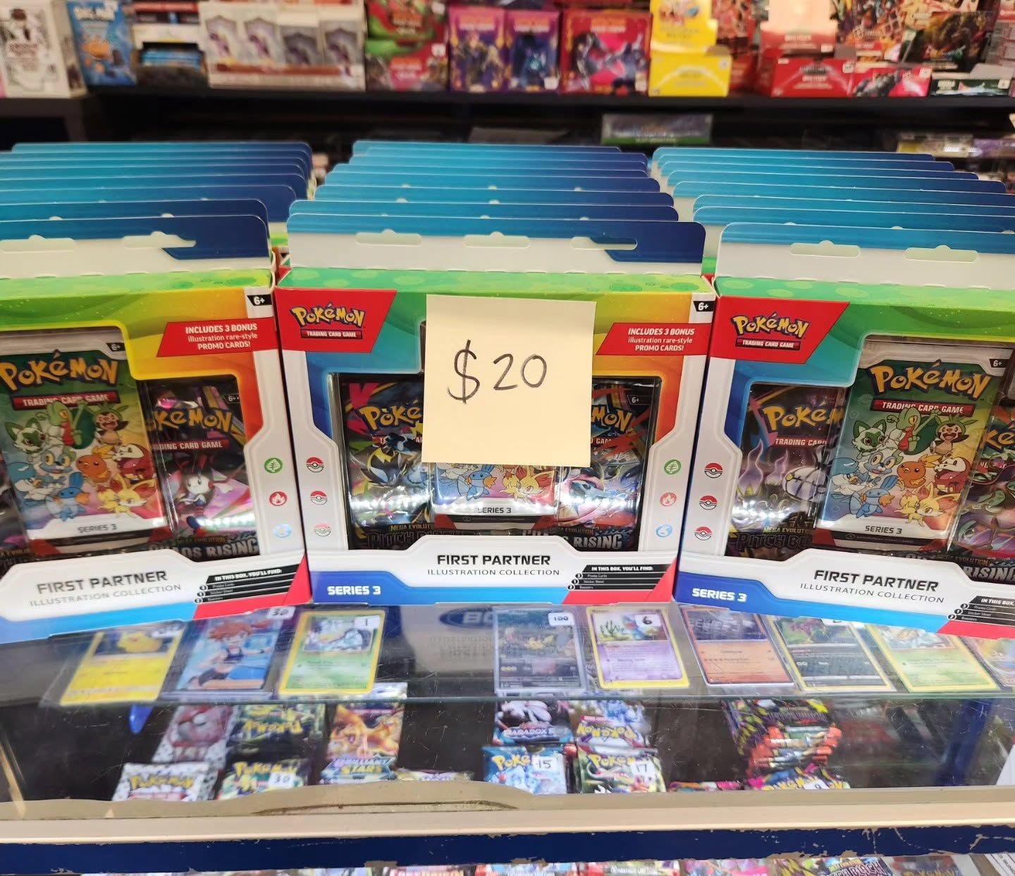 Pokémon trading cards and boxes on display, with a $20 sign at a store counter.