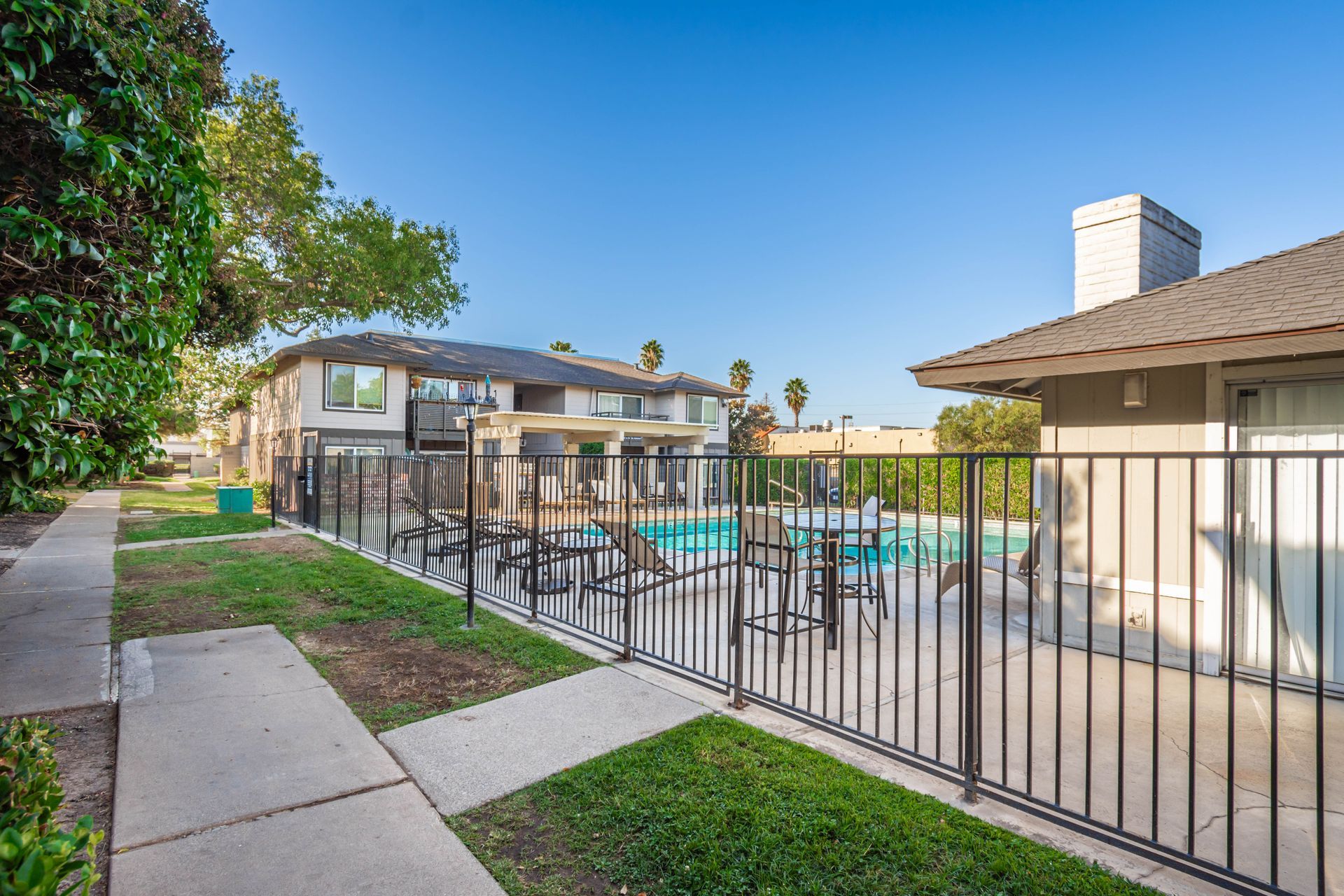 A fence surrounds a swimming pool in a residential area.