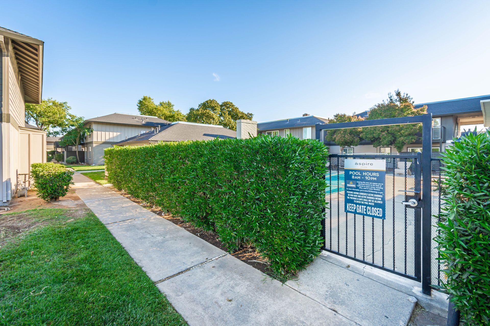 A fence surrounds a swimming pool in a residential area.