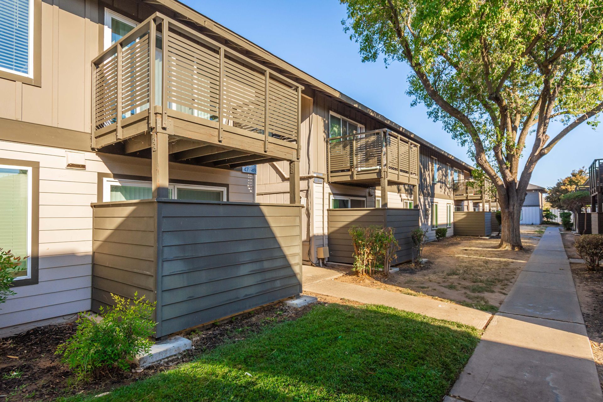 A row of apartment buildings with balconies and a sidewalk.