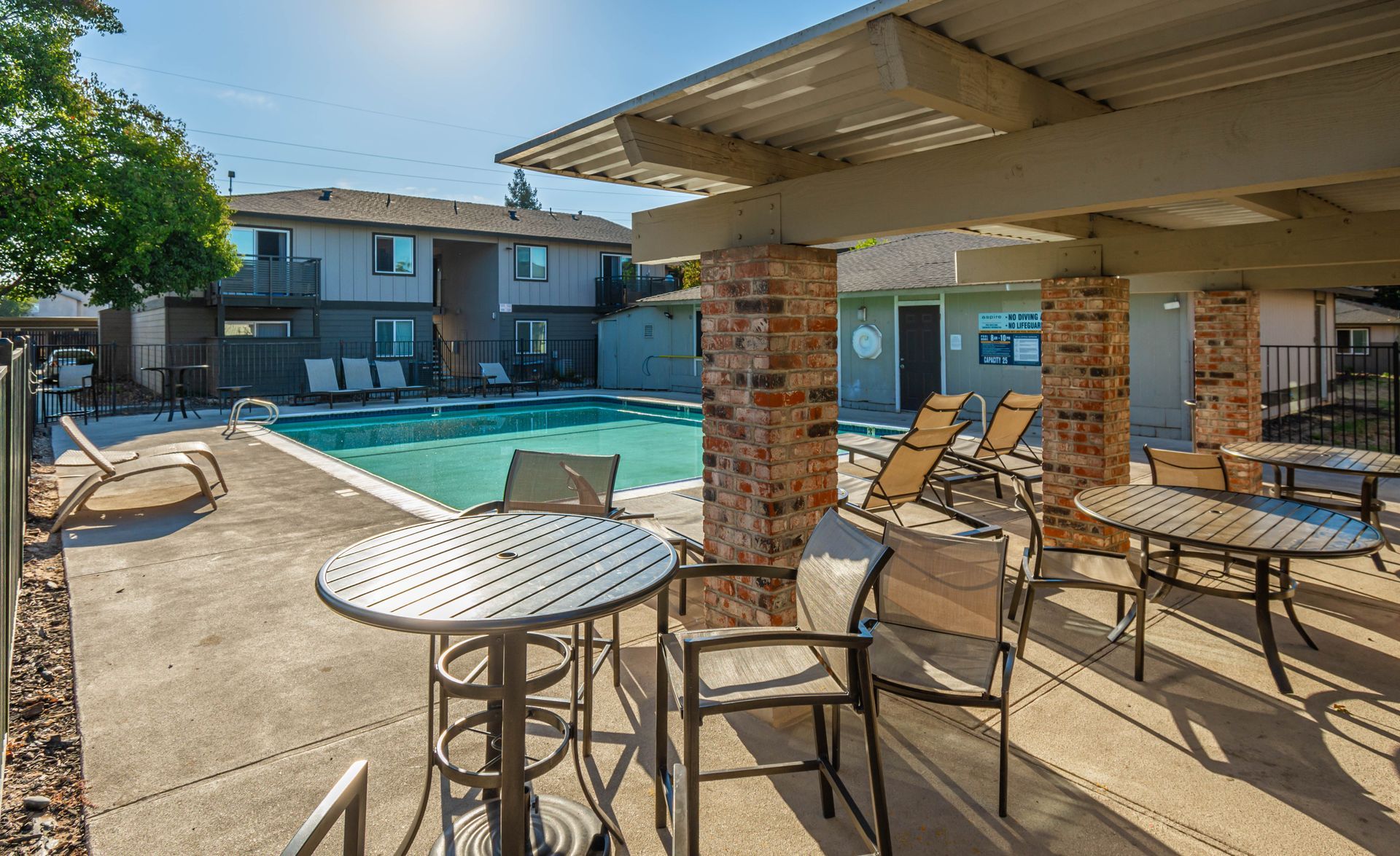 A patio area with tables and chairs next to a swimming pool.