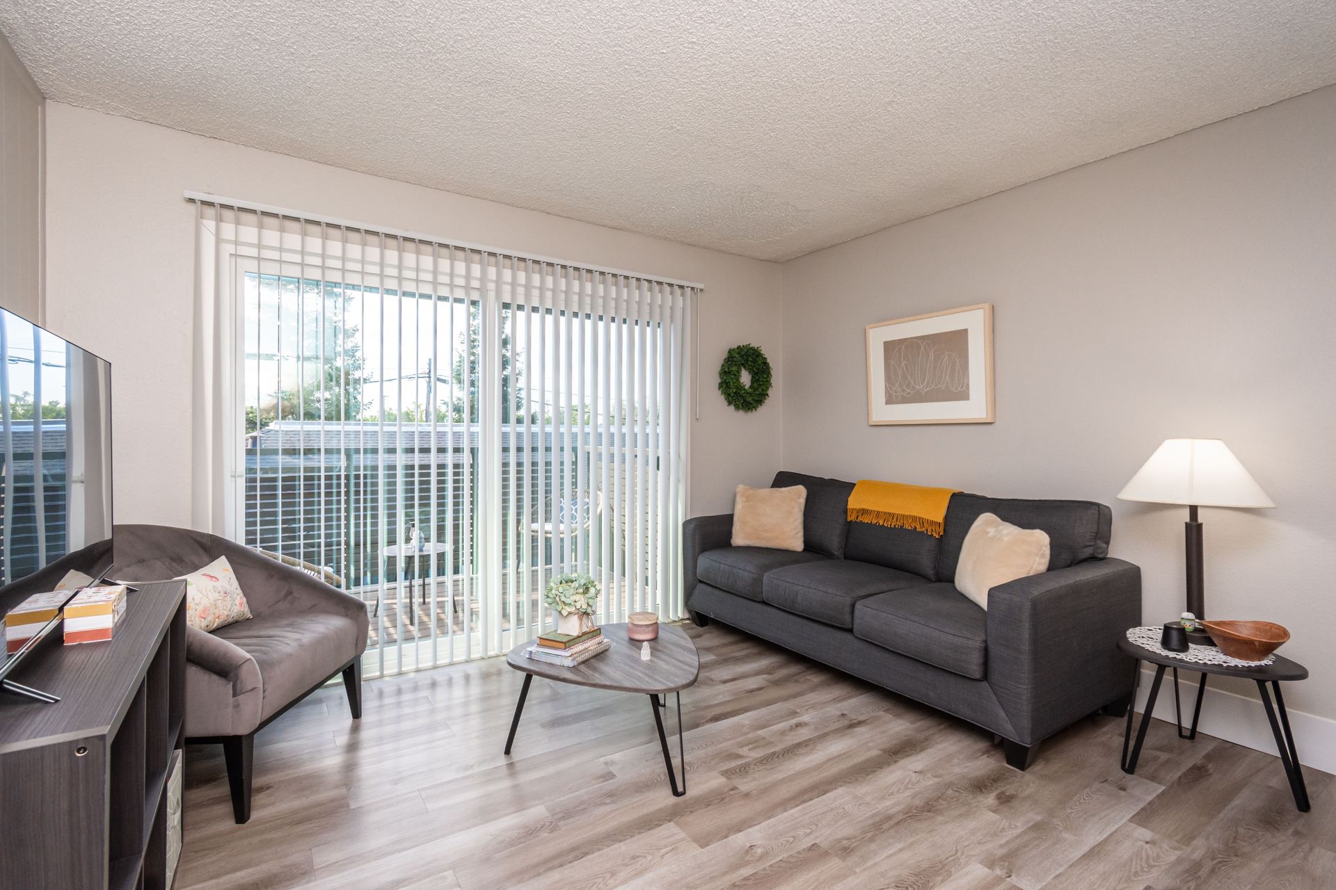 A living room with a couch , chair , coffee table and sliding glass doors.