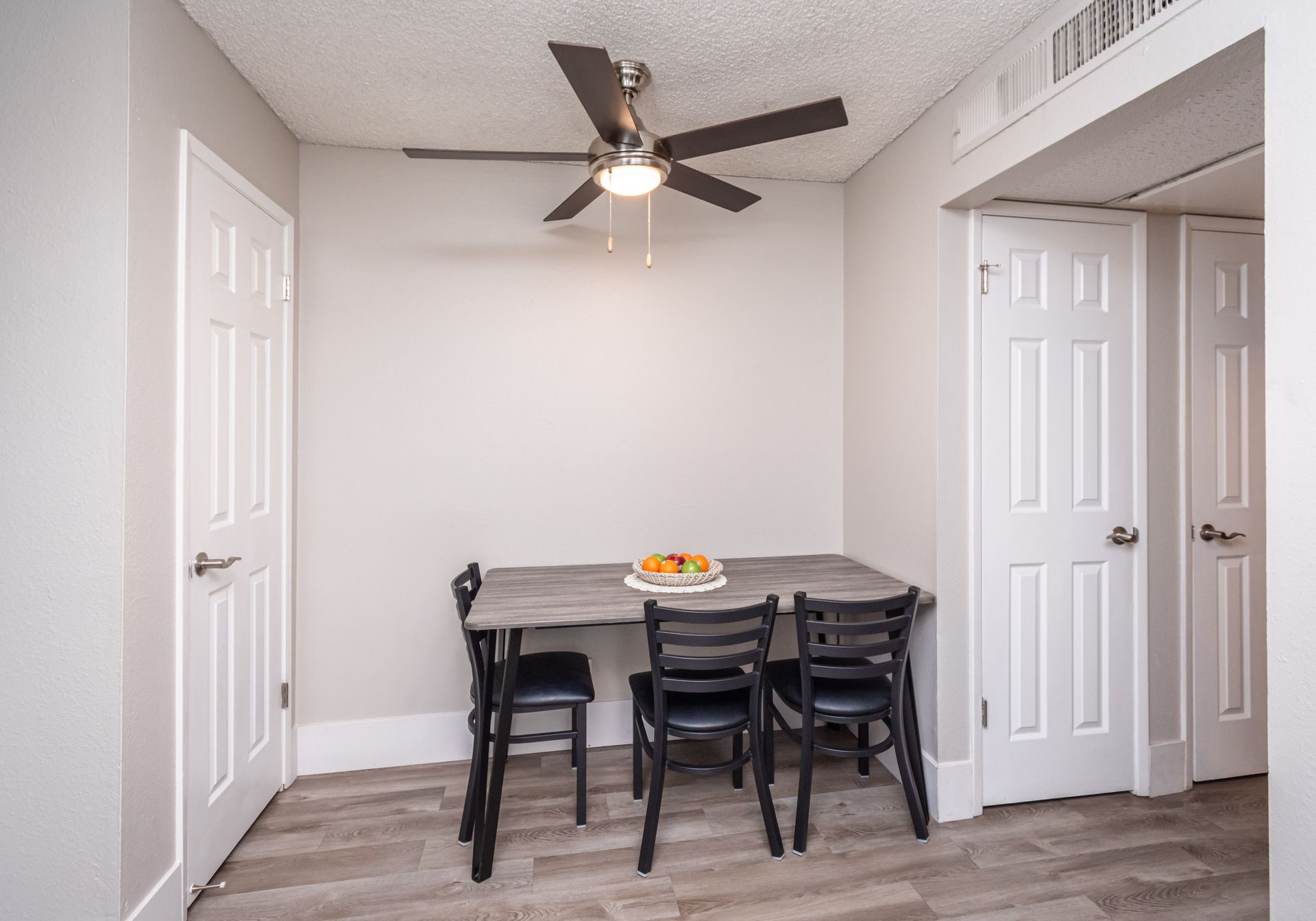 A dining room with a table and chairs and a ceiling fan.