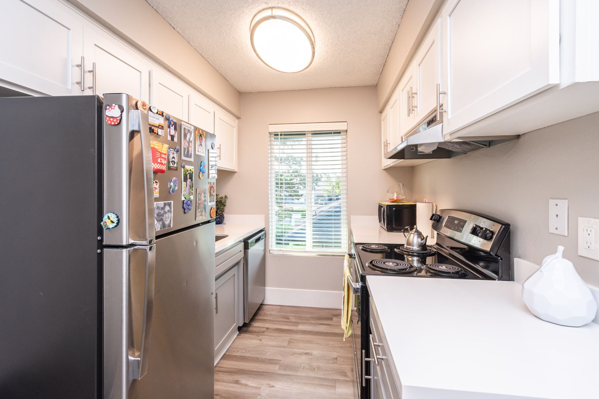 A kitchen with stainless steel appliances , white cabinets , a refrigerator and a stove.