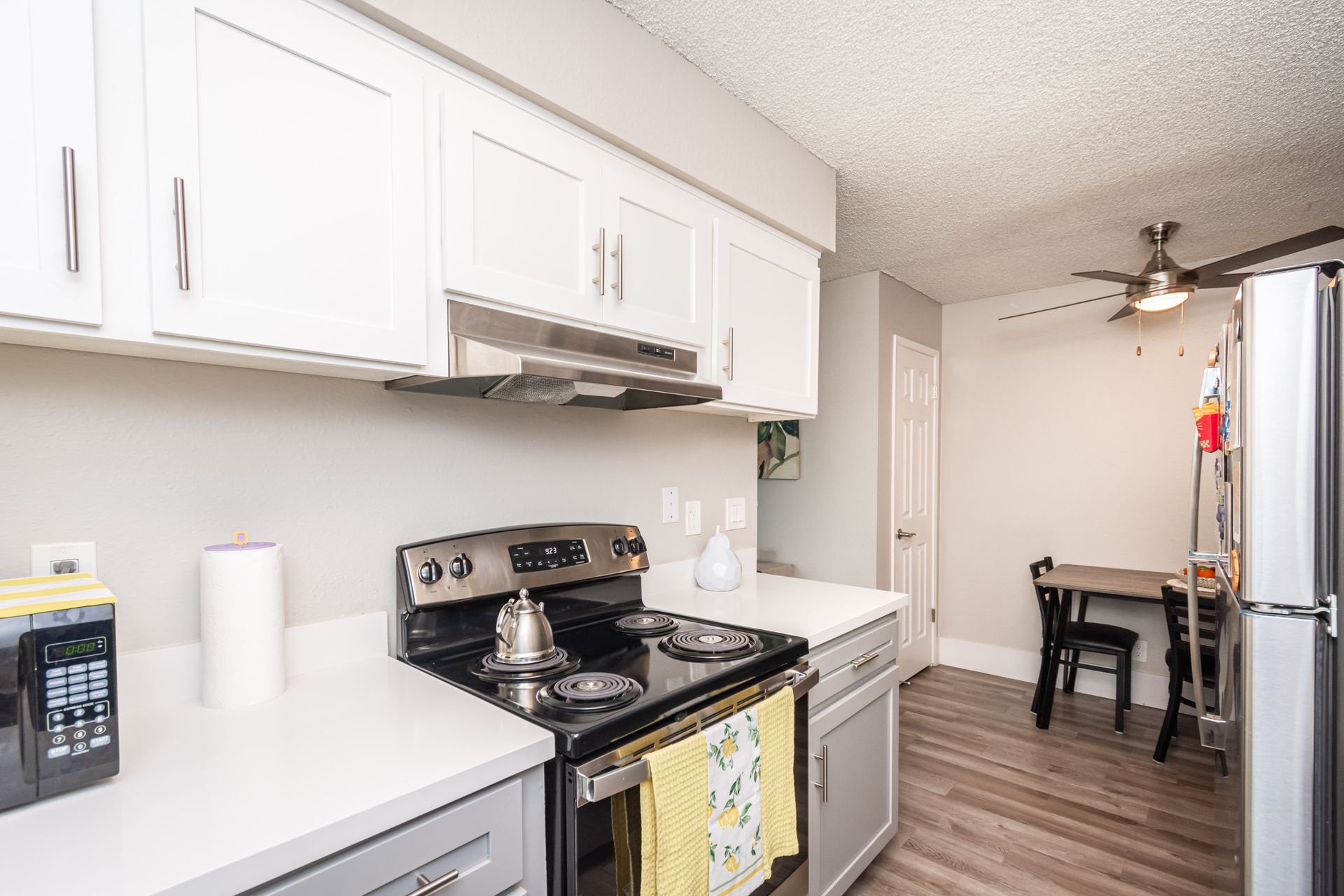 A kitchen with a stove , refrigerator , table and chairs.