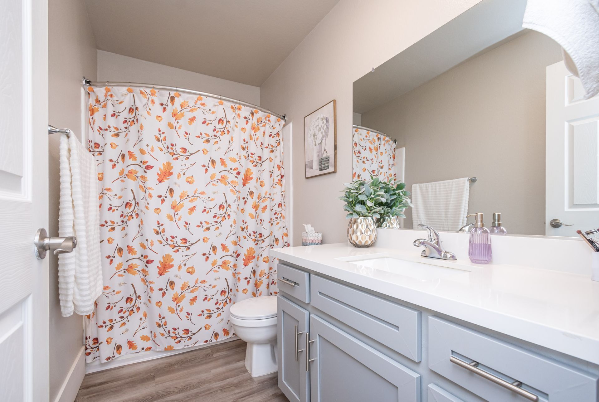 A bathroom with a toilet , sink , mirror and shower curtain.