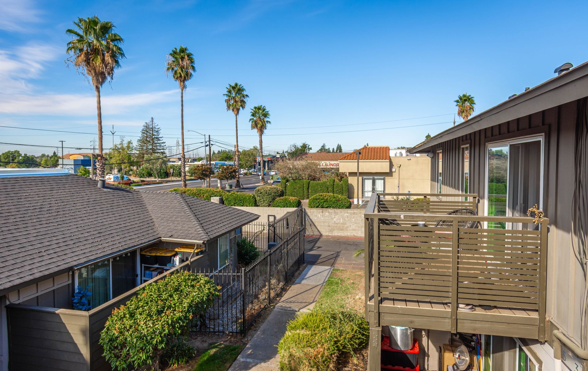 A view of a building with a balcony and palm trees in the background.