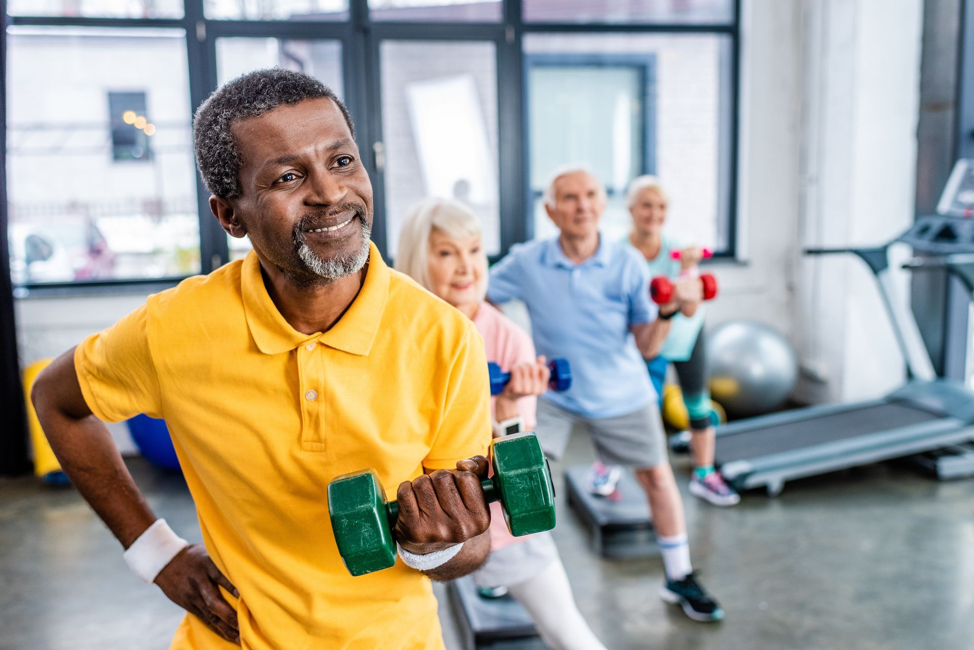 A group of elderly people are lifting dumbbells in a gym.