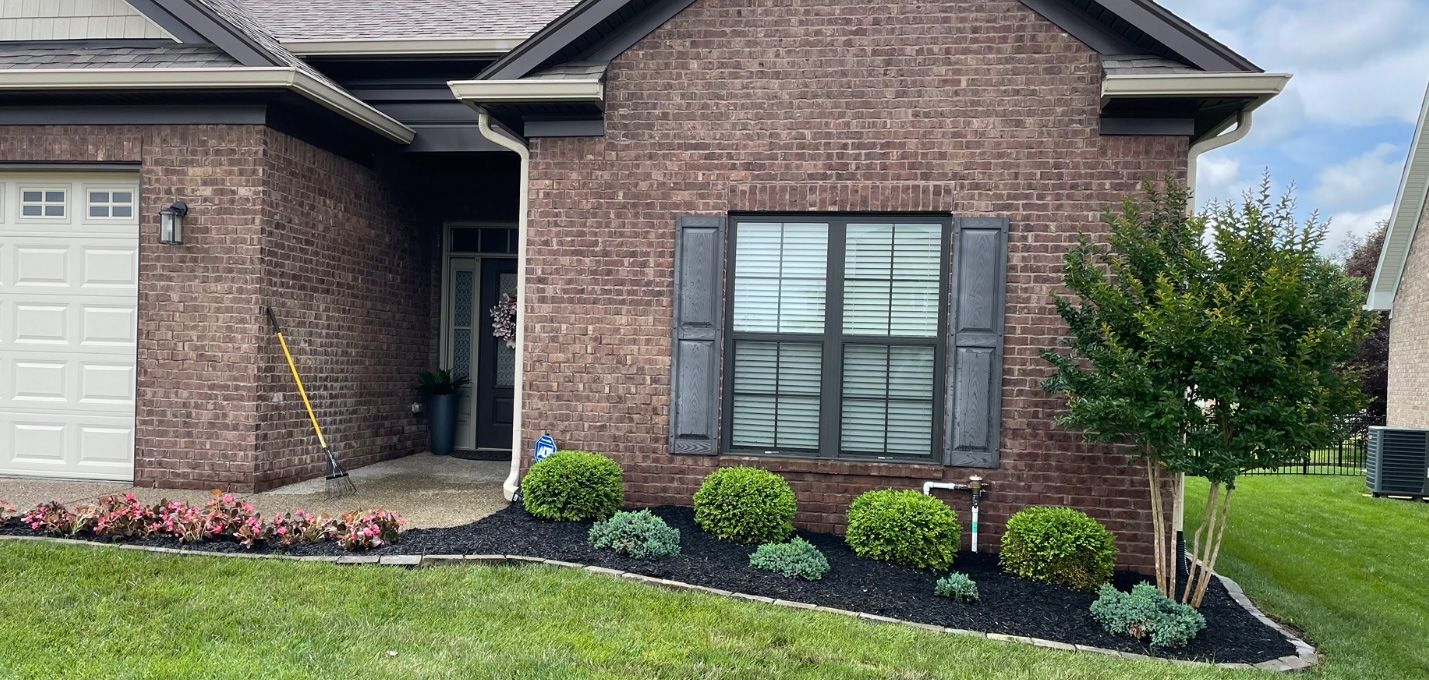 A brick house with a lush green lawn in front of it.