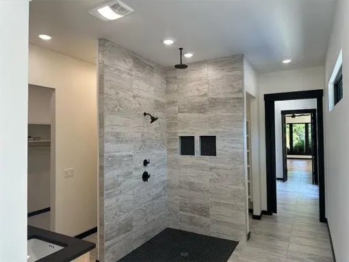 Modern bathroom featuring a walk-in shower with grey stone-look tiles, black fixtures, and a black pebble shower floor.