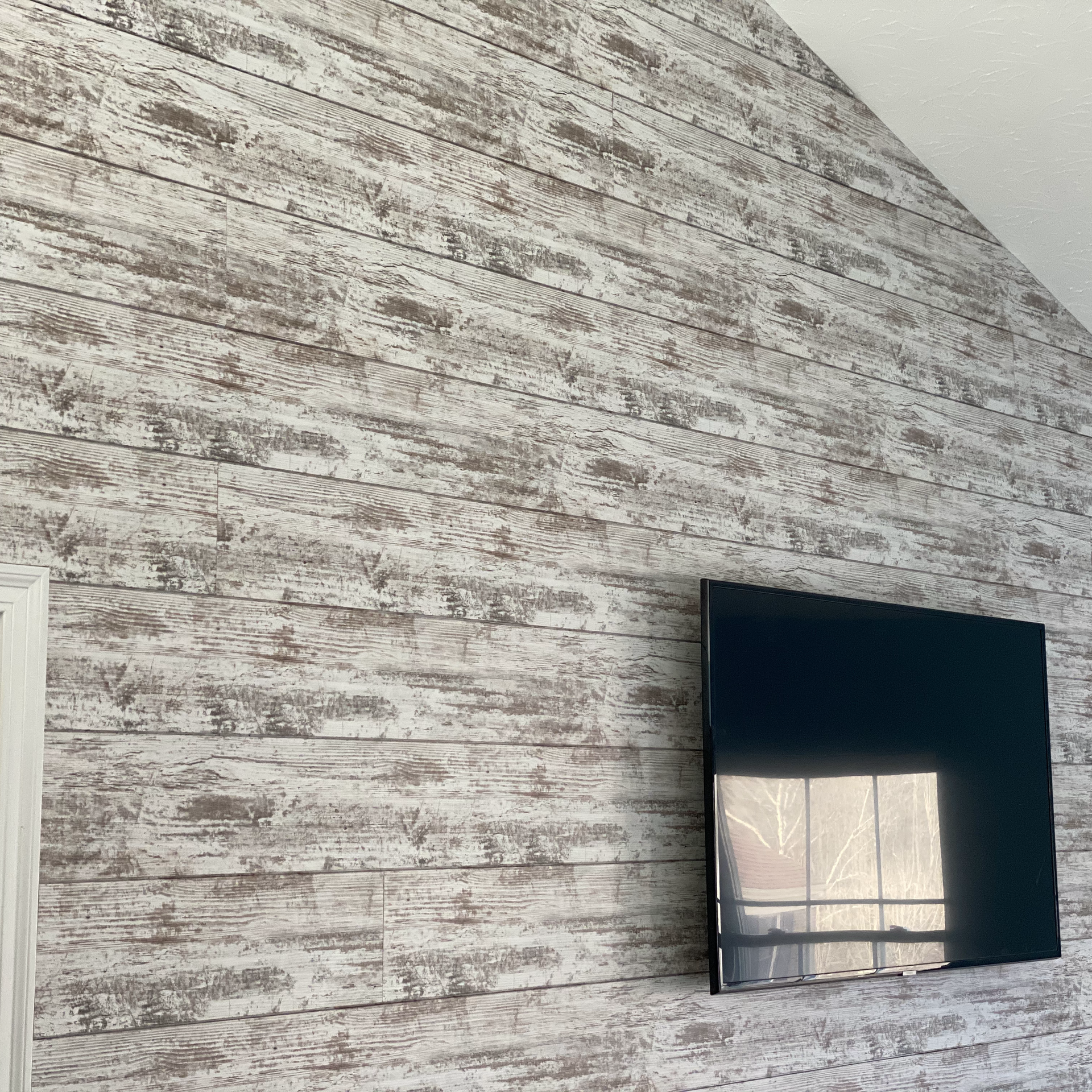 A flat screen tv is mounted on a wall with a brick wall behind it.