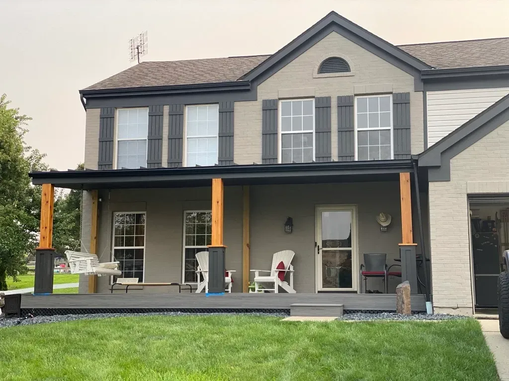 A large house with a porch and chairs in front of it.