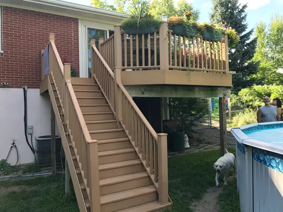 A wooden deck with stairs leading up to it next to a pool.