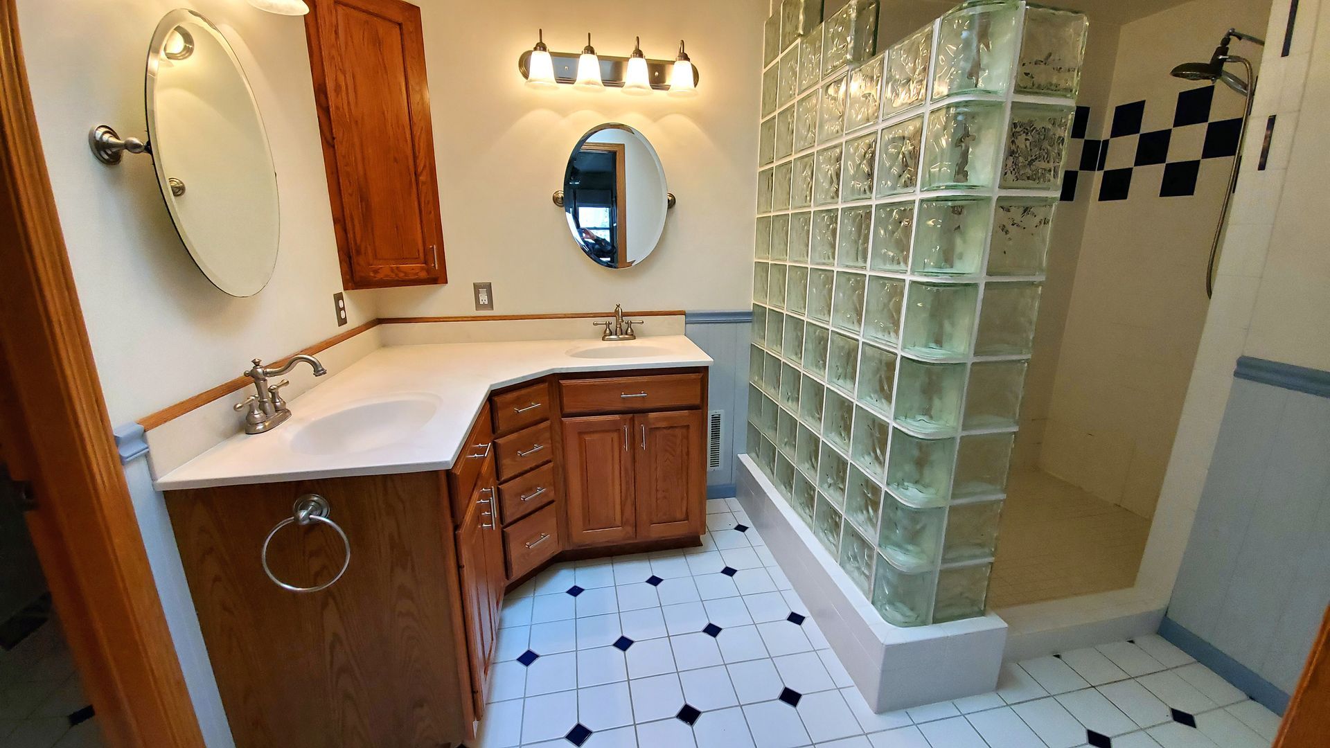 A bathroom with a glass block shower and a mirror