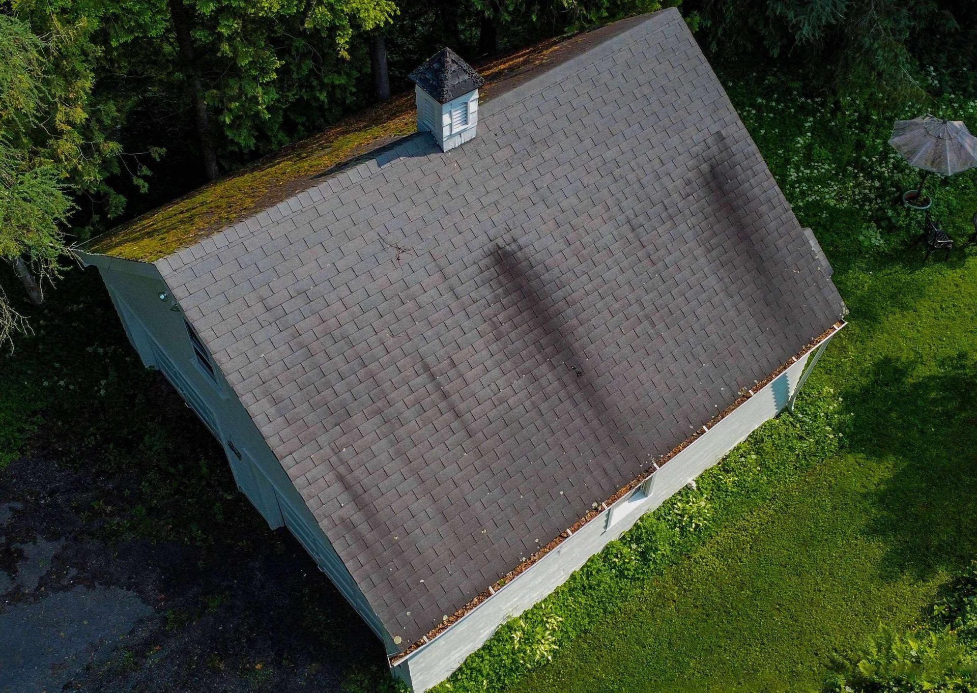 An aerial view of a house with a roof that is covered in moss