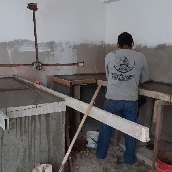 Un trabajador enyesará una pared en una habitación sin terminar utilizando soportes de madera y herramientas de construcción.