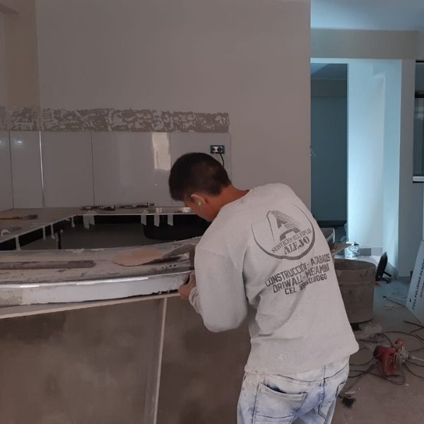 Trabajador instalando una encimera curva en una zona de cocina sin terminar.