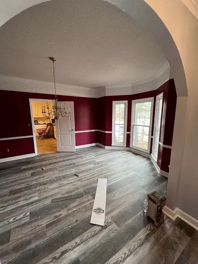 Empty living room with maroon walls, gray wood flooring, arched ceiling, and French doors to the outside