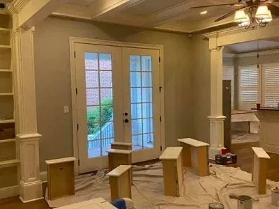 Freshly painted living room with cardboard floor protectors and French doors to a patio