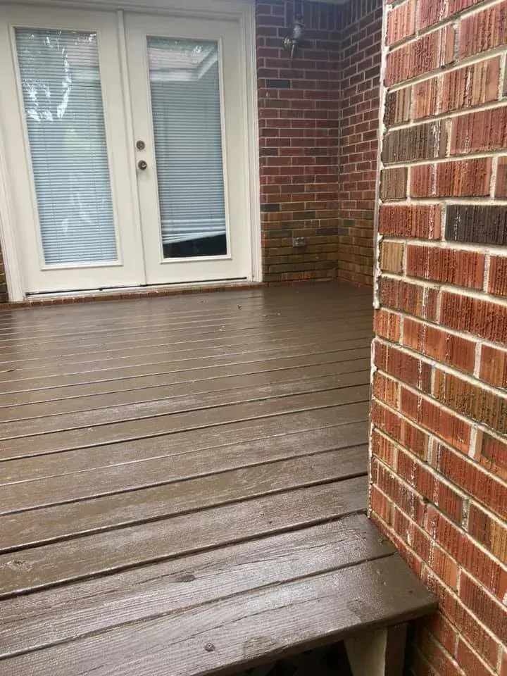 Wooden deck with French doors and brick walls, viewed from a corner corner