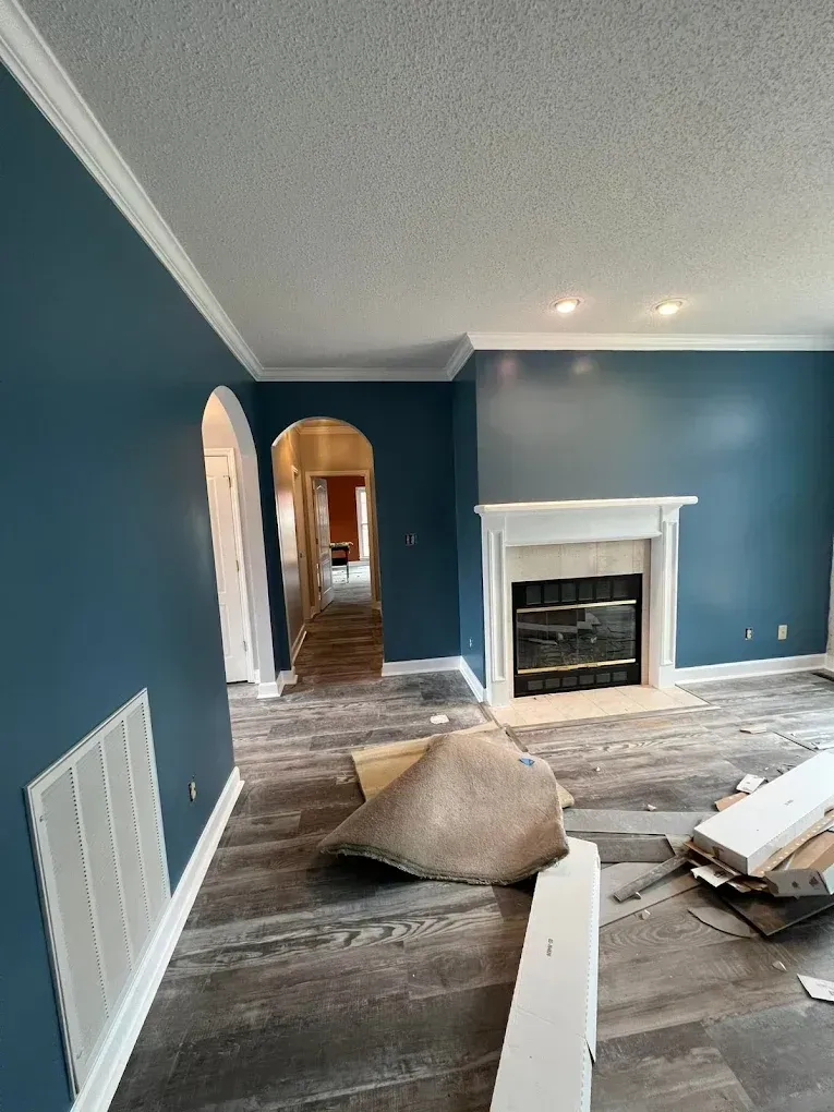 Living room under renovation with blue walls, fireplace, arched doorway, and construction debris on the floor