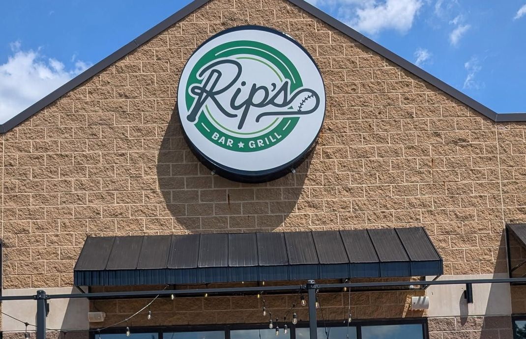 Rip’s Bar & Grill sign on a tan brick building with a black awning against a blue sky