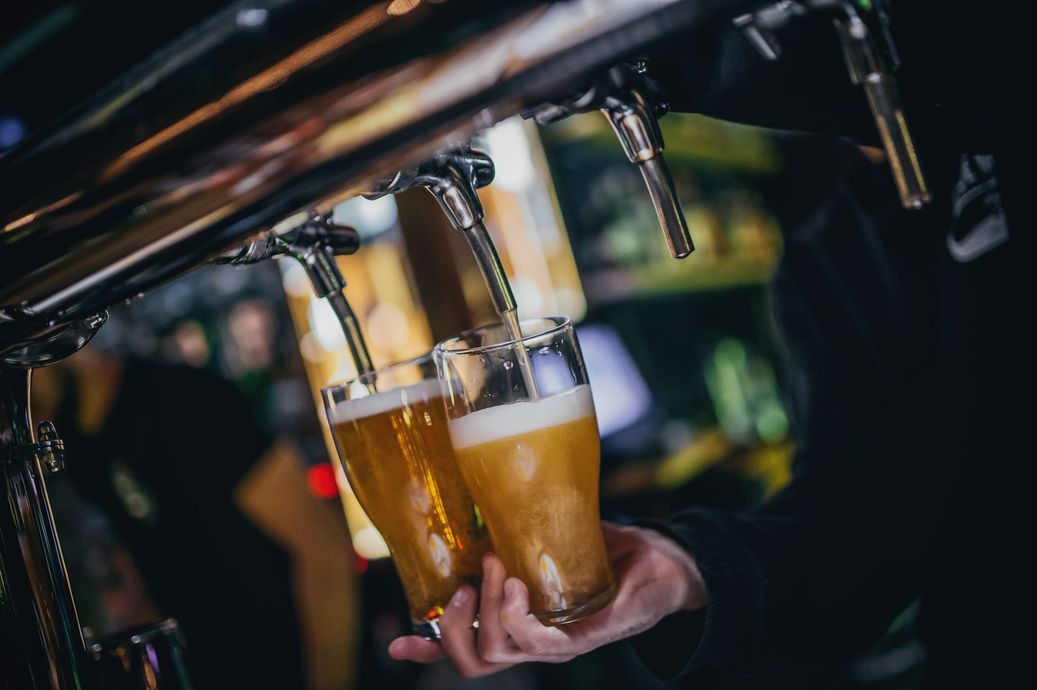 Beer glasses being filled from taps at a dimly lit bar