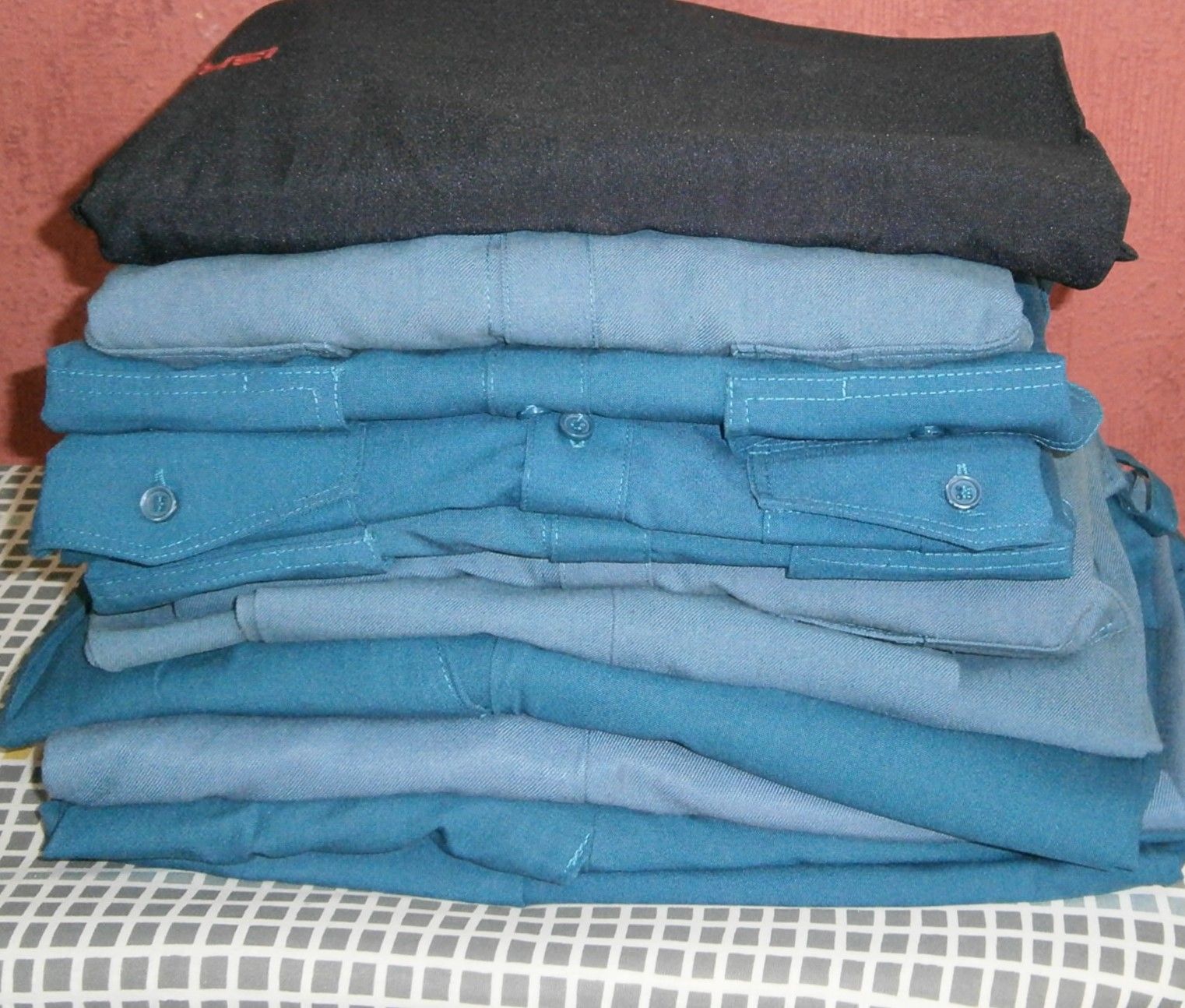 Una pila de camisas dobladas en tonos azules, coronada con una camisa negra