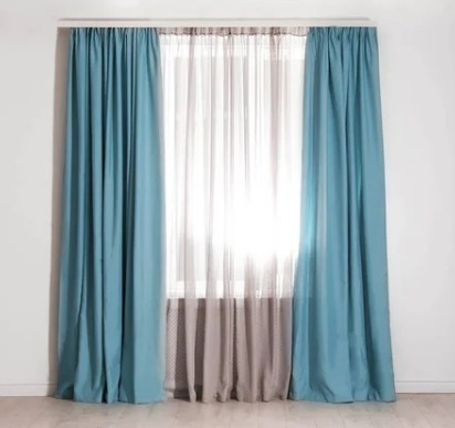 Una ventana cubierta por dos cortinas azules opacas a los lados y una cortina transparente de color claro en el centro.