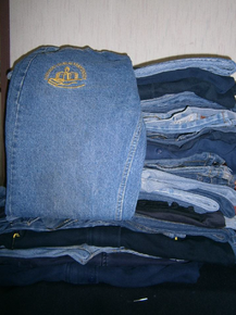 Varias chaquetas de trabajo azules con tiras reflectantes de seguridad colgadas en un perchero.