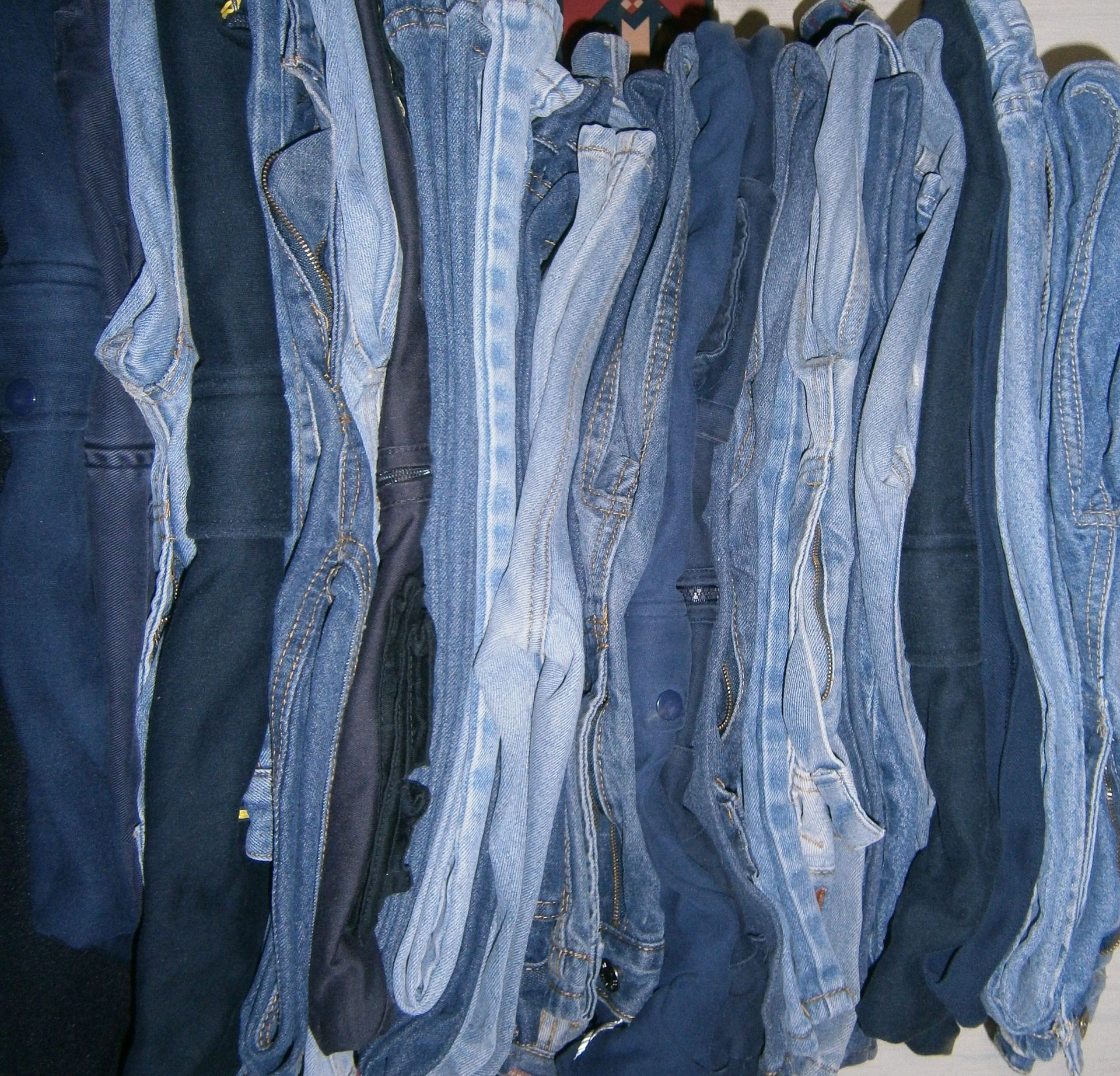 Un perchero con pantalones vaqueros colgados juntos, mostrando varios tonos de azul, desde claro hasta oscuro.