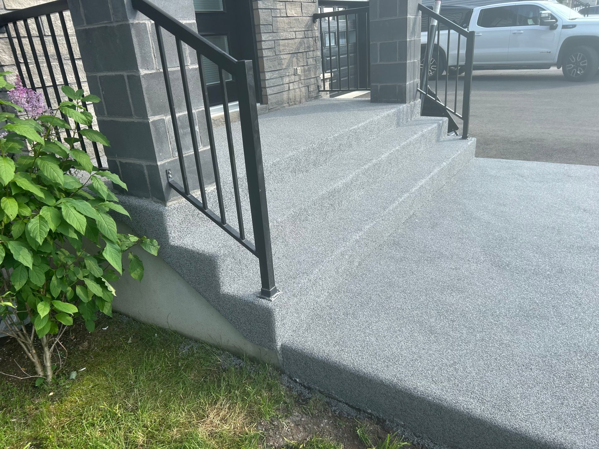 Un porche en béton avec escalier et rampe en métal.