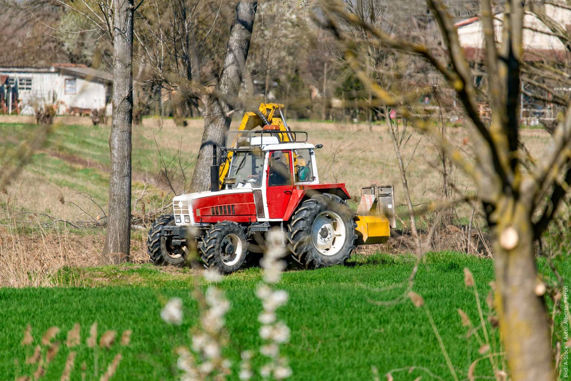 Rot-weißer Traktor der den Graben reinigt