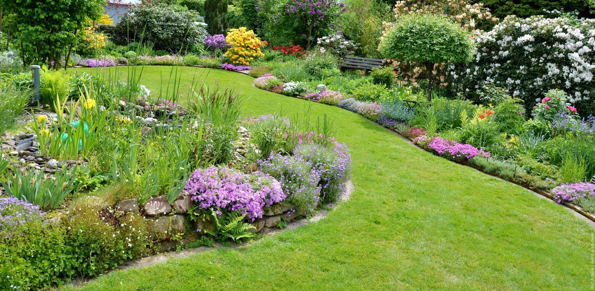 Garten nach der Umgestaltung mit gepflegtem Rasen und Blumenbeeten