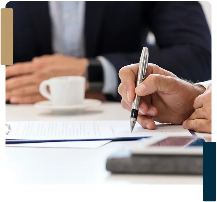 A man is writing on a piece of paper with a pen.