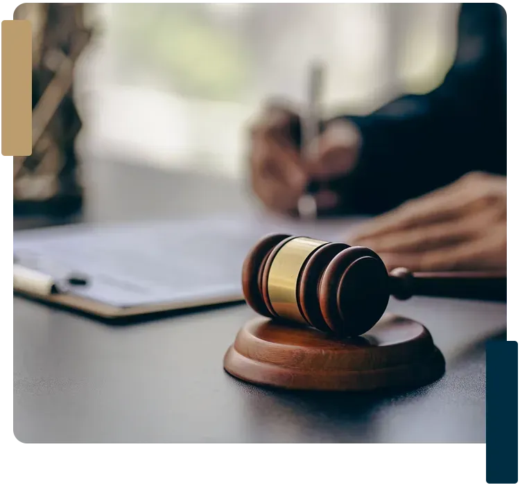 A judge 's gavel is sitting on a table next to a person writing on a clipboard.