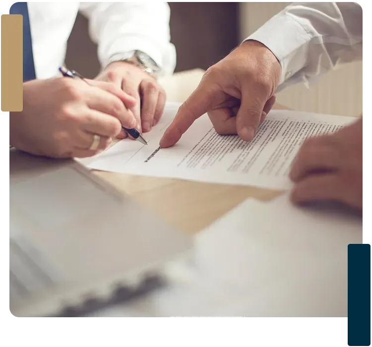 A person is pointing at a piece of paper while another person signs it