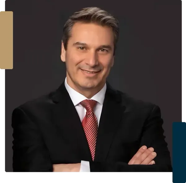 A man in a suit and tie is smiling with his arms crossed