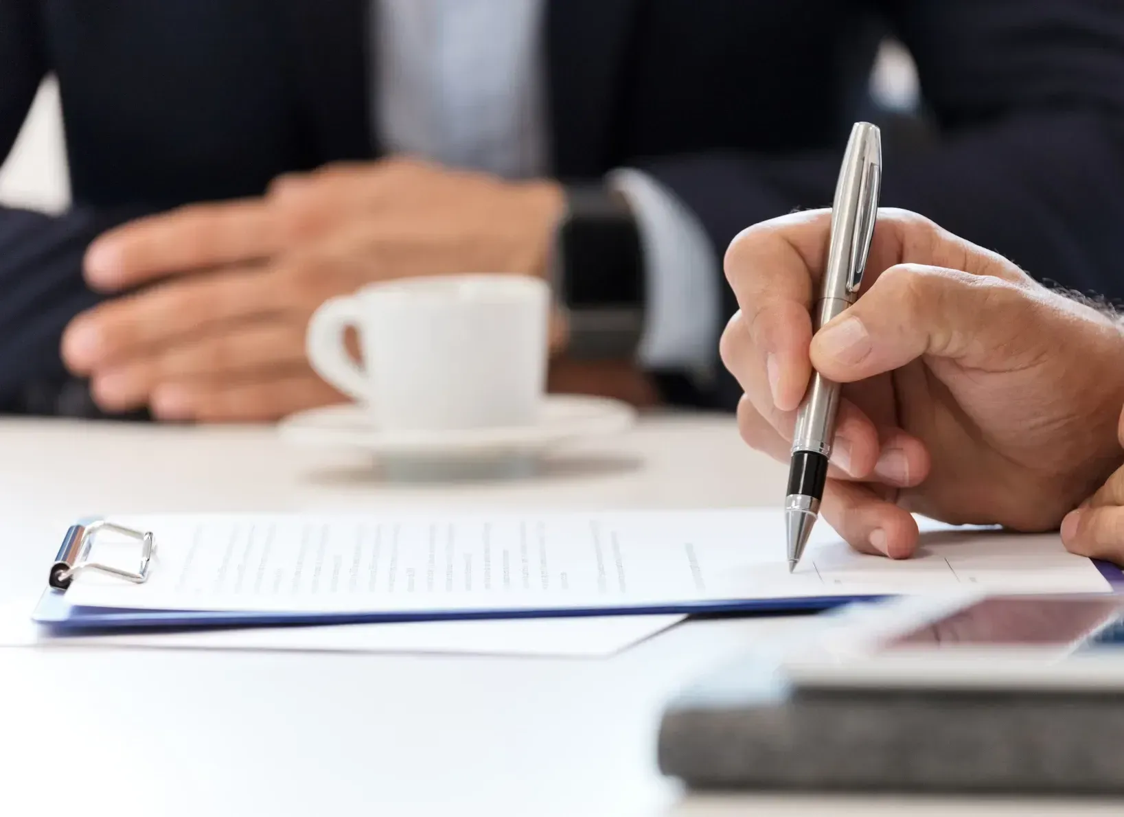 A person is writing on a clipboard with a pen.