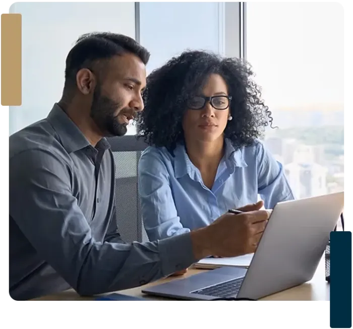 A man and a woman are looking at a laptop computer.
