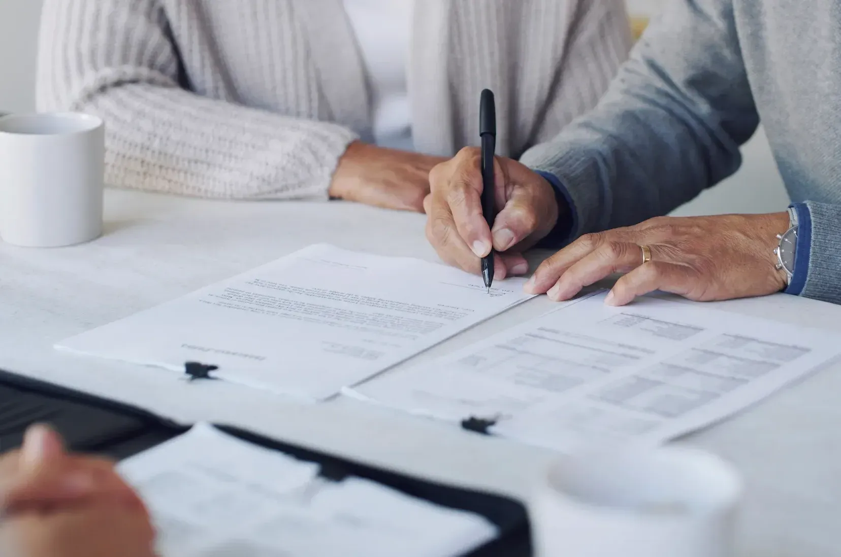 A man and a woman are sitting at a table signing a document.