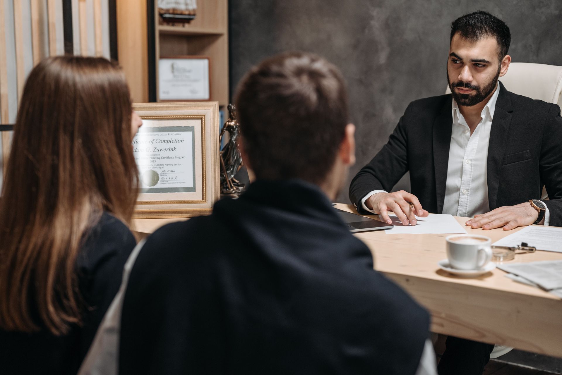 Two people meeting with a businessman at a desk in a modern office