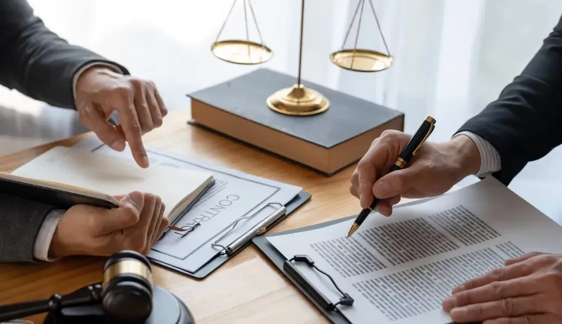 A group of people are sitting at a table with a judge 's gavel and scales of justice.