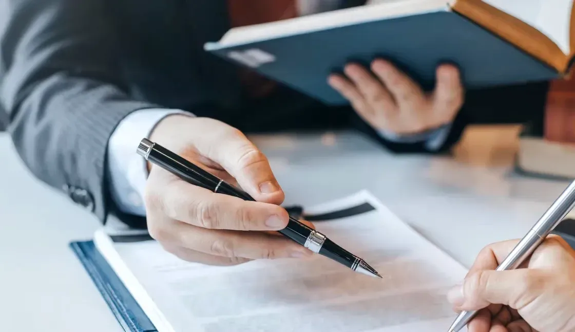 A person is holding a pen over a piece of paper.
