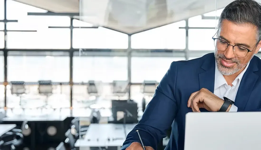 A man in a suit is sitting in front of a laptop computer.