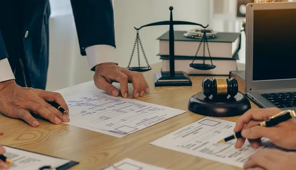 A group of lawyers are sitting at a table with papers and a laptop.