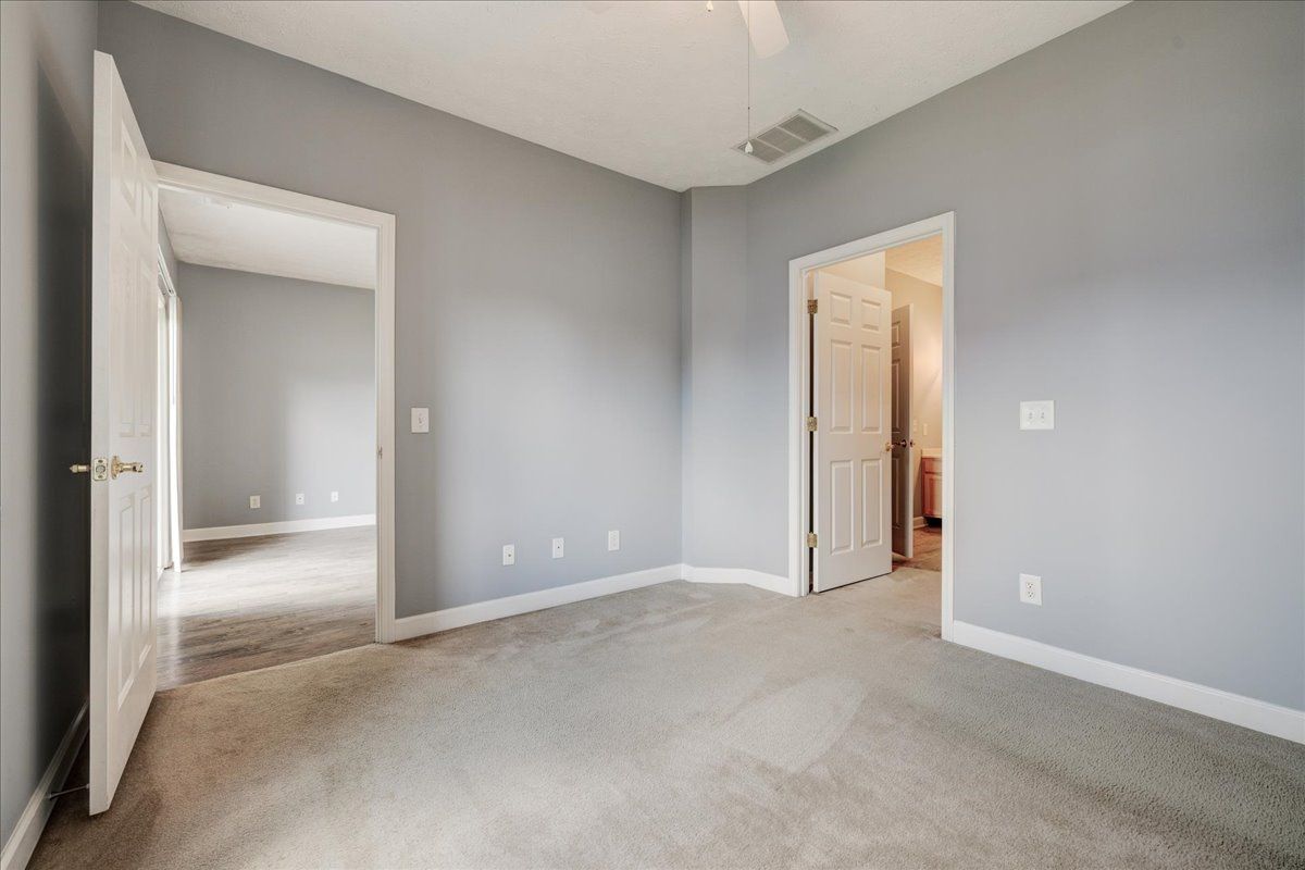 An empty bedroom with gray walls and a ceiling fan.