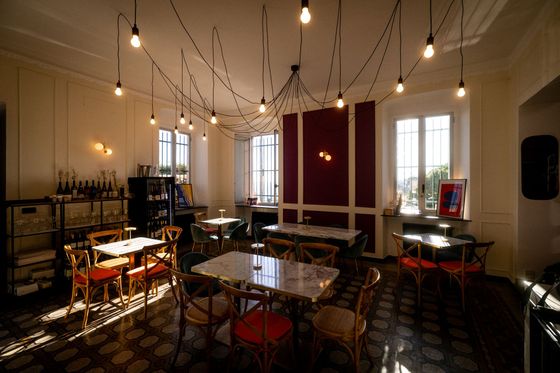 Studio di musica illuminato da una luce calda, con lampadine a sospensione, strumenti e sedie disposte attorno a un tavolo centrale.